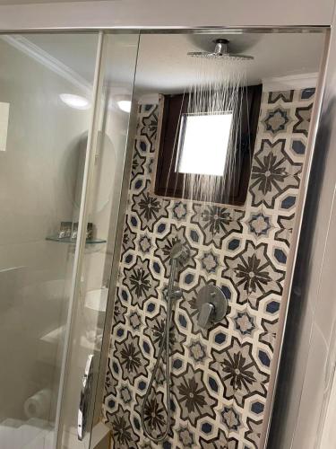 a bathroom with a shower and a tile wall at House Marianthi Anthoula in Sarti