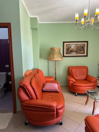a living room with a leather chair and a lamp at Roy Apartments in Durrës