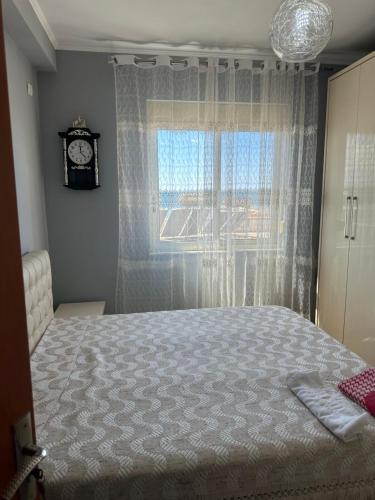 a bedroom with a bed and a window with a clock at Roy Apartments in Durrës