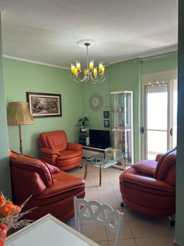 a living room with red leather furniture and a chandelier at Roy Apartments in Durrës