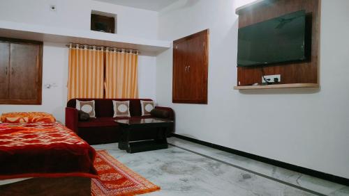 Laxmanji villas في مونت ابو: غرفة نوم مع سرير وتلفزيون على الحائط
