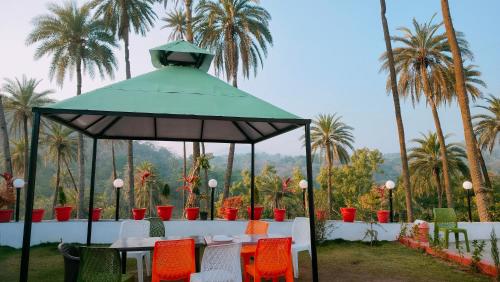 altana z krzesłami, stołami i palmami w obiekcie Laxmanji villas w mieście Abu