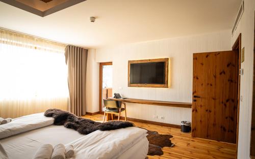 a bedroom with two beds and a desk and a television at HANUL BUCOVINEI in Câmpulung Moldovenesc