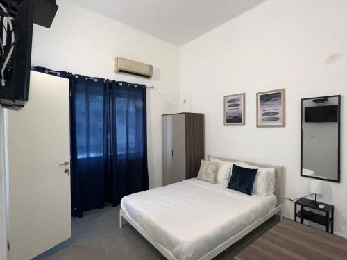 1 dormitorio con cama blanca y cortinas azules en Carmel Market center apartments TLV, en Tel Aviv