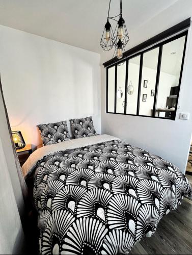 une chambre avec un lit avec une couette noire et blanche dans l'établissement Joli appartement avec parking, à La Rochelle