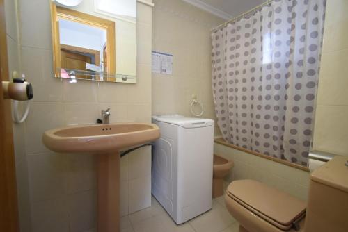 a bathroom with a sink and a toilet and a mirror at CASTELMAR 2 DORMITORIOS - Fincas Arena in Benidorm