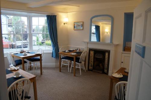 ein Esszimmer mit 2 Tischen und einem Kamin in der Unterkunft Radcliffe Guest House in Ross on Wye