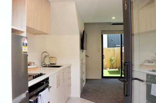 a kitchen with white cabinets and a door leading to a yard at Cute on Cashel 6 in Christchurch