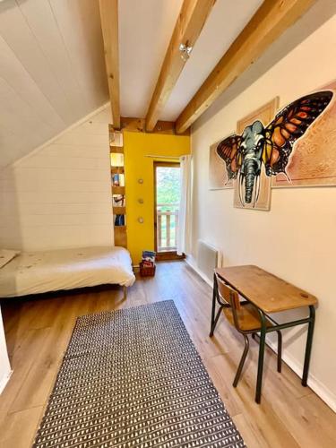 une chambre avec un lit et une table avec un papillon sur le mur dans l'établissement Maisonnette au cœur du village, à Châteauvieux
