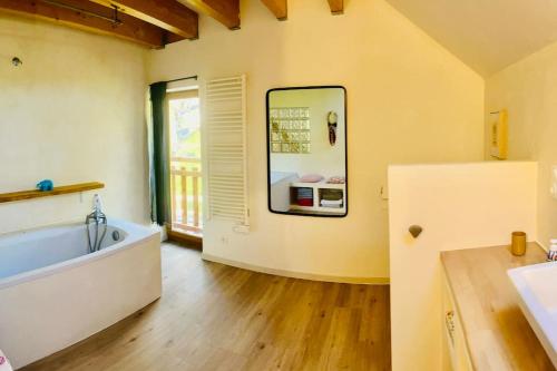 une salle de bain avec baignoire et une grande fenêtre dans l'établissement Maisonnette au cœur du village, à Châteauvieux