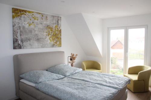 um quarto branco com uma cama e 2 cadeiras em Neu saniertes Haus in Hermaringen für 9 Personen! Nähe Legoland! 