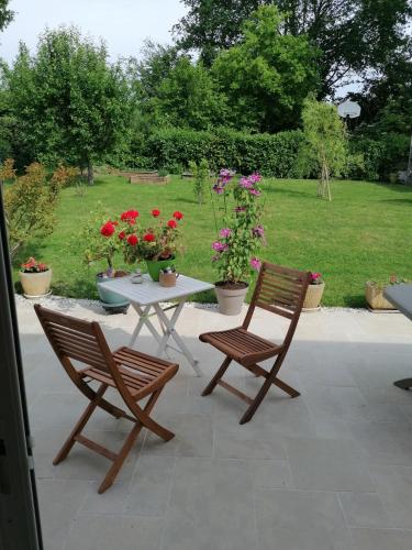 un patio con due sedie e un tavolo con fiori di Chambre d'hôte au calme a Le Mans