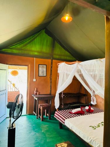 Un dormitorio con una cama y un escritorio en una tienda de campaña. en Animal View Point Yala, en Tissamaharama