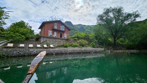 a house sitting on the side of a river with a boat at Borealis Guest House in Koman