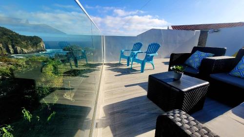 eine Terrasse mit Stühlen und Tischen und Meerblick in der Unterkunft Casa da Praia dos Moinhos in Ribeira Grande