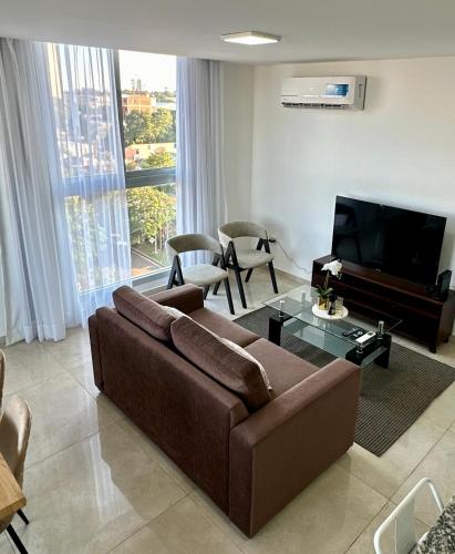 a living room with a brown couch and a flat screen tv at Rio Suits Apartments A in Posadas