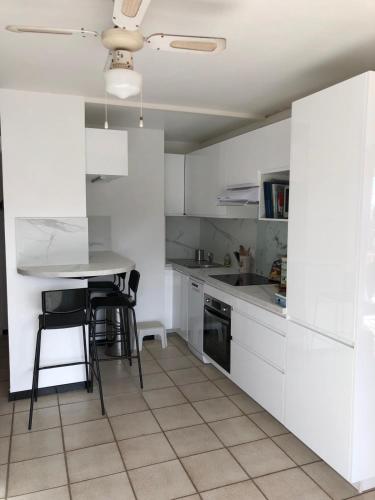 une cuisine avec des armoires blanches et une table et des chaises dans l'établissement Appart 2 p presqu'ile de Giens plage Bergerie, à Hyères