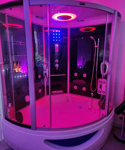 een badkamer met een douche met roze verlichting bij Chambre LOVE ROOM 35m2 avec LIT ROND Balnéo Hammam vidéoprojecteur in Jardin