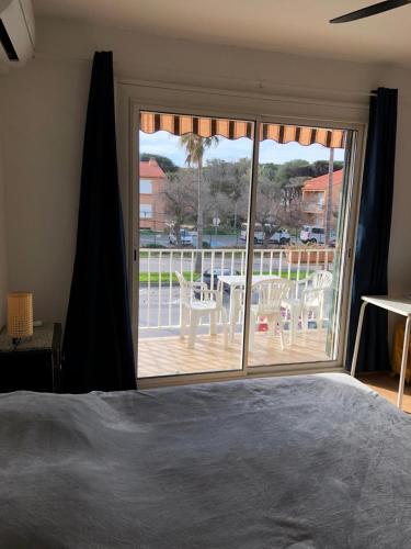 - une chambre avec une grande porte coulissante en verre donnant sur une terrasse dans l'établissement Appart 2 p presqu'ile de Giens plage Bergerie, à Hyères