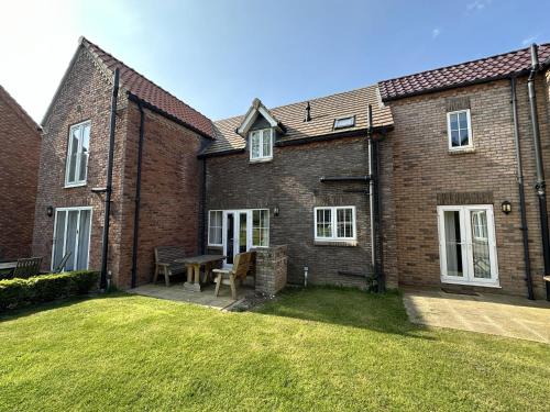 a brick house with a picnic table in the yard at Nantucket Cottage - Part of the The Bay Filey Holiday Village with pool, gym and direct beach access, pub, restaurant, tennis and meadows walks in Filey