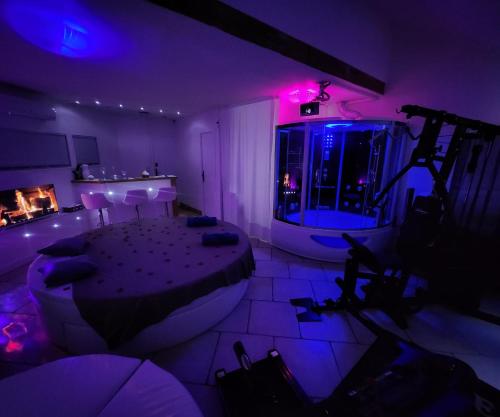 een kamer met een bad en een kamer met paarse verlichting bij Chambre LOVE ROOM 35m2 avec LIT ROND Balnéo Hammam vidéoprojecteur in Jardin