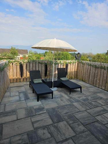 a patio with two chairs and an umbrella at Croí Beag Luxury Studio Omeath in Dundalk