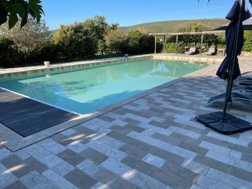 - une piscine avec un parasol et une chaise dans l'établissement Gîtes les Eygries, à Ongles