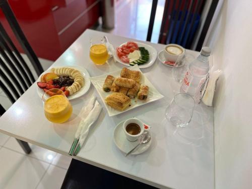 une table avec deux assiettes de nourriture et deux verres de jus d'orange dans l'établissement Hotel Europa Kruje, à Krujë