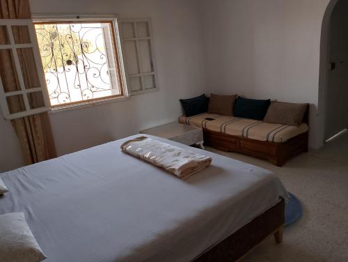 ein Schlafzimmer mit einem Bett, einem Sofa und einem Fenster in der Unterkunft Dar ettawfik in Tataouine