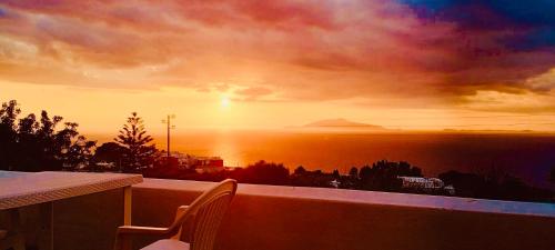a view of a sunset from a balcony with a chair at About Capri in Anacapri