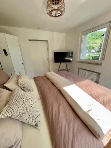 a bedroom with a bed with a window and a television at DAS AMBIENTE II Komfortables Wohnerlebnis mit Moselromantik - Herzlich Willkommen - in Zell an der Mosel