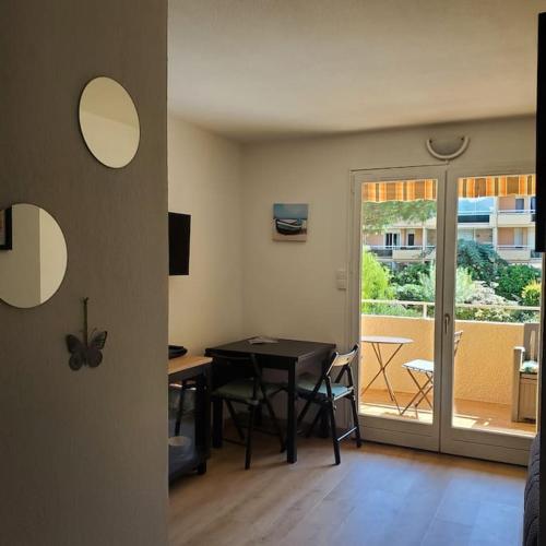 une salle à manger avec une table et un balcon dans l'établissement Délicieux Studio 3 p climatisé La Faviere, à Bormes-les-Mimosas