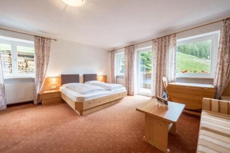 a bedroom with a bed and a table and windows at Gasthof Innerwalten in San Leonardo in Passiria