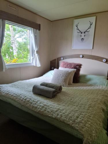 a bedroom with a bed with two pillows and a window at Caravan Turnberry 2 in Port Seton