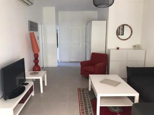 - un salon avec une télévision et une chaise rouge dans l'établissement Appartement au cœur de Cannes, à Cannes