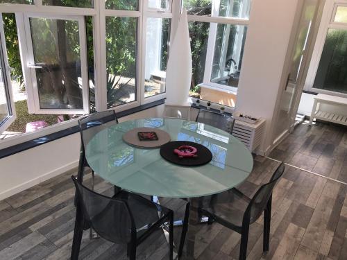 une table en verre avec des chaises et un chapeau dessus dans l'établissement Appartement au cœur de Cannes, à Cannes
