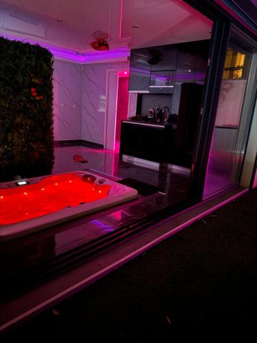 Cette chambre dispose d'une baignoire avec des lumières violettes. dans l'établissement Love Room Romantique, à Villiers-sur-Marne