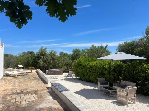 a patio with an umbrella and chairs and tables at Trullo La Quercia in Ostuni