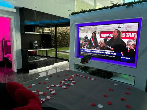 une pièce avec une table avec des roses et une télé dans l'établissement Love Room Romantique, à Villiers-sur-Marne