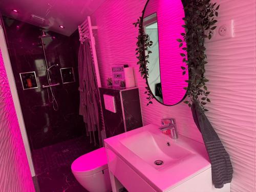 une salle de bain rose avec un lavabo et un miroir dans l'établissement Love Room Romantique, à Villiers-sur-Marne