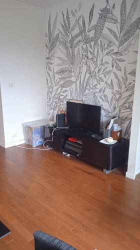 - un salon avec une télévision au-dessus d'une table dans l'établissement 2 pièces avec terrasse à Chatou, à Rueil-Malmaison