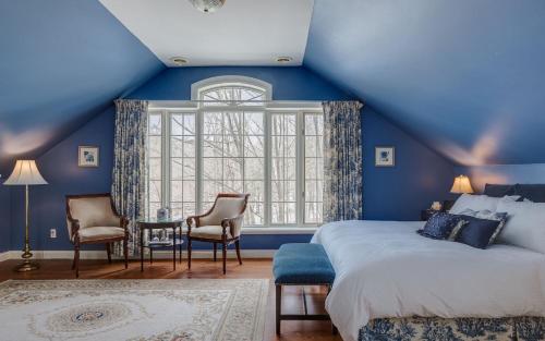 ein blaues Schlafzimmer mit einem Bett und einem Fenster in der Unterkunft Manoir Sweetsburg in Cowansville