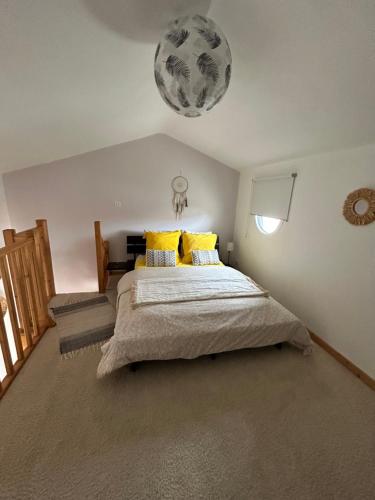 a bedroom with a large bed with yellow pillows at La Petite Chaunière in Saint-Fulgent