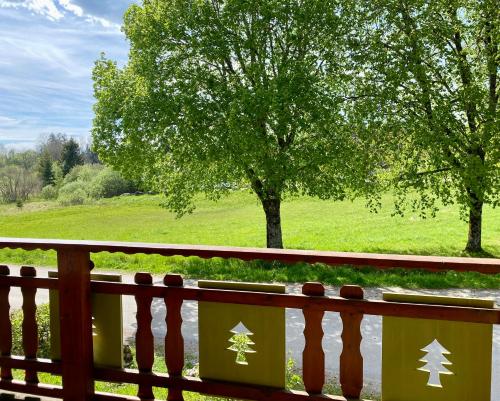 a wooden fence with a tree in a field at Chalet des Moineaux in Saint-Laurent-en-Grandvaux