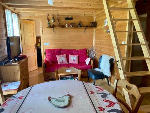 a living room with a red couch and a ladder at Chalet des Moineaux in Saint-Laurent-du-Jura