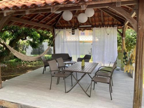 eine Terrasse mit einem Tisch, Stühlen und einer Hängematte in der Unterkunft Chaleureux Studios Martinique in Fort-de-France