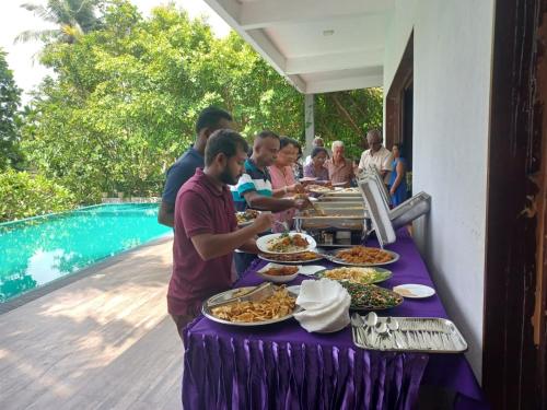 a group of people standing around a table with food at Thalangama Lakeview Lodge in Battaramulla