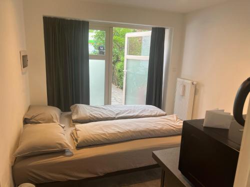 een kamer met 2 bedden voor een raam bij Cosy in Mechelen