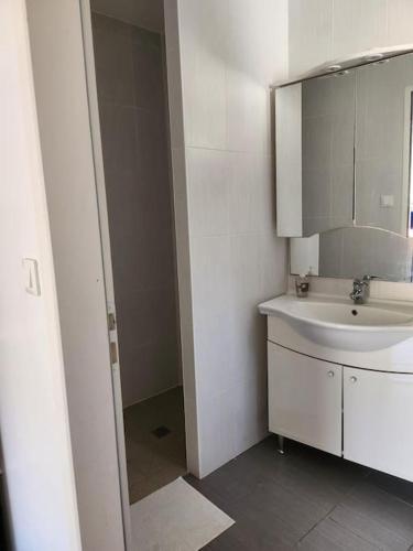 une salle de bain blanche avec un lavabo et un miroir dans l'établissement Charmante maison à 2 pas du lac de Biscarosse, à Biscarrosse