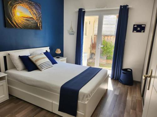une chambre avec un lit aux murs bleus et une fenêtre dans l'établissement Charmante maison à 2 pas du lac de Biscarosse, à Biscarrosse